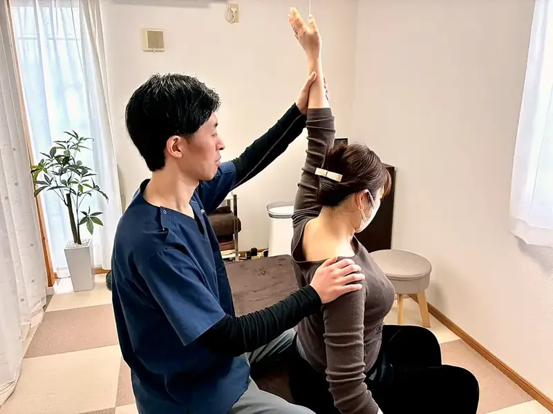 腕を挙げてもらい、肩に手を添えて動きを確かめている様子