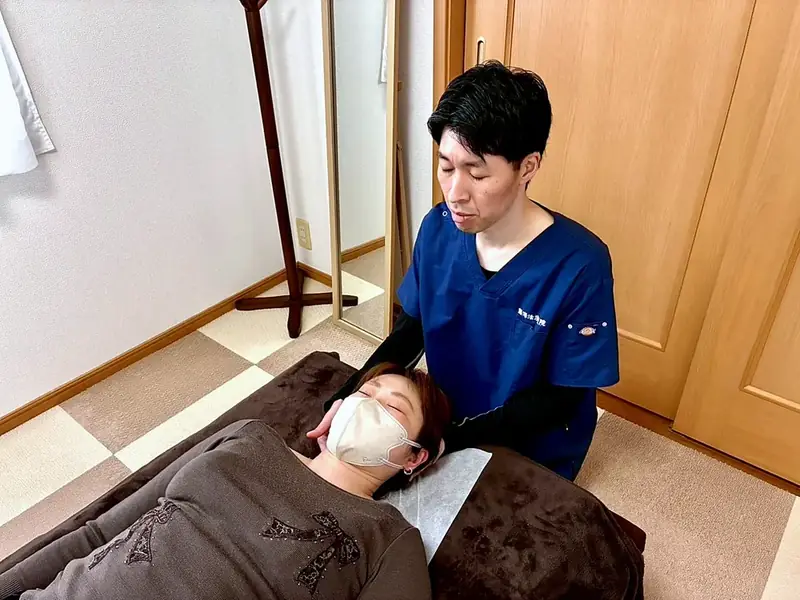 首まわりに手を当てて施術している様子