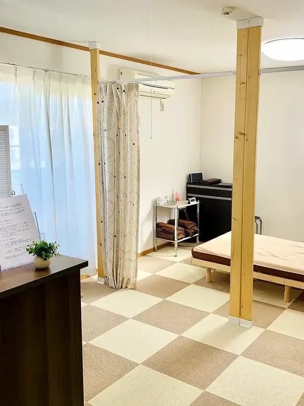 院内。手前に受付カウンター、仕切りカーテンの奥に施術ベッド